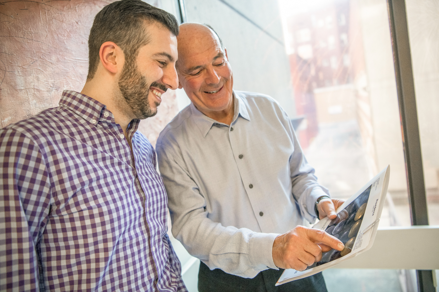 Image of Dr. William Ross and retina fellow Dr. Nakhoul look at a document, smiling.