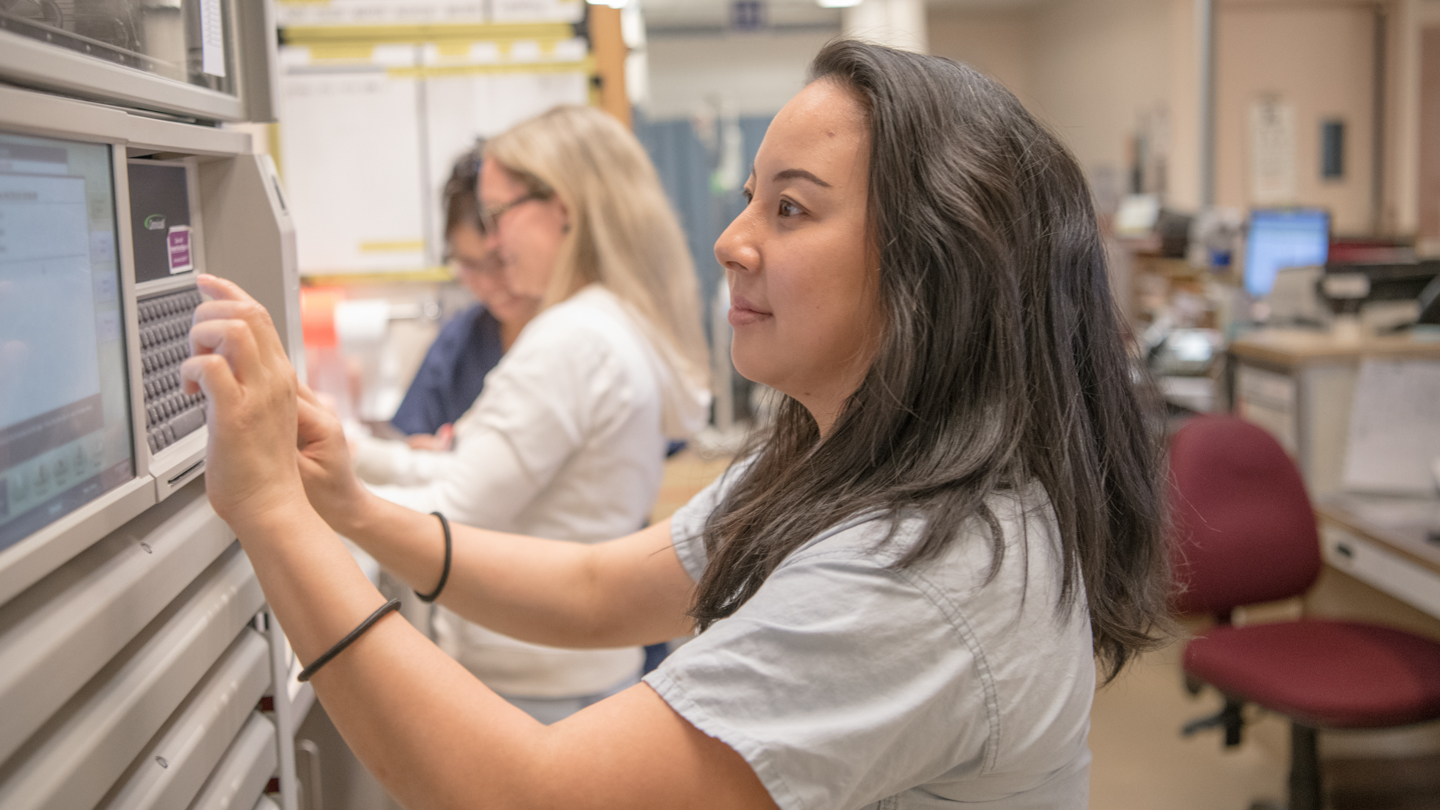 Image of a woman typing on a screen in a medical setting